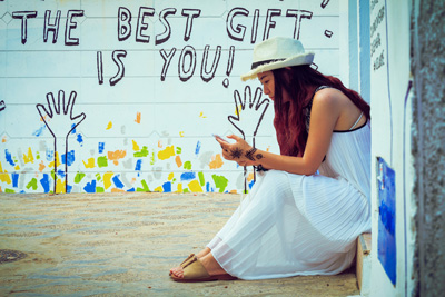 Woman in white sitting in front of a graffiti wall.