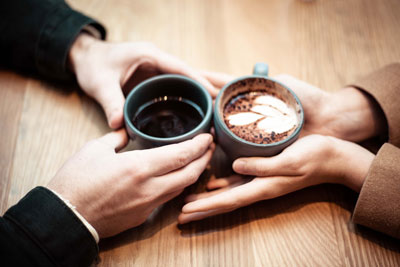 two people holding coffee on mugs